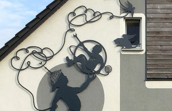 Ansicht Hausfassade mit Arbeit "Wolkenfangen" (figürliche Silhouetten aus Aluminium) von wolf v. Waldow in Goyatz, Spreewald