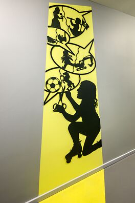 Lebensort Vielfalt Berlin, Projekt Storyboard – scherenschnittartige Figur aus Stahl auf Wand von Wolf v. Waldow, Motiv: Mädchen zerschneidet Sprechblasen mit Jungen- bzw Mädchenspielzeug.