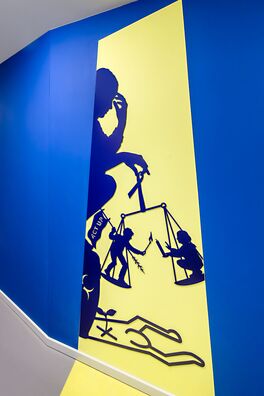Lebensort Vielfalt Berlin, Projekt Storyboard – scherenschnittartige Figur aus Stahl auf Wand von Wolf v. Waldow, Motiv: trauernede Frau sitzt auf Urne mit Act-up Fahne, auf dem Boden Keith-Haring-Figur.