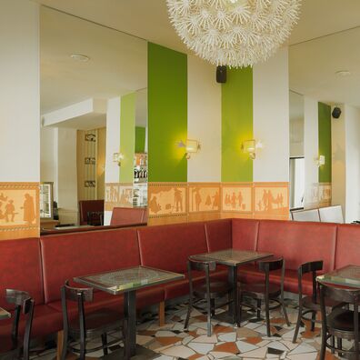 Blick in den vorderen Gastraum des Café Bierhimmel Berlin mit Tapetenfries (Imitation von figürlichen Holzintarsien) von Wolf v. Waldow; Wandflächen abwechselnd grün u. weiß gestrichen; rote Polsterbänke