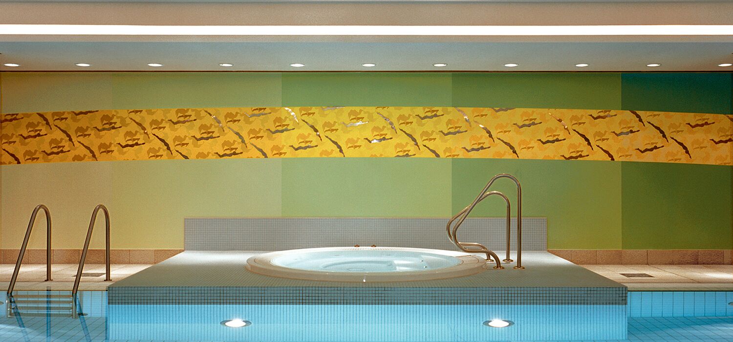 Schwimmbad Hotel Meridien Hamburg mit Wandarbeit H2O II von Wolf v. Waldow: Wasserbecken, Rückwand in Farbverlauf von hell- bis dunkelgrün, darauf gebogener Streifen mit Ornament aus Kamelen in Gelb und aufgesetzen, polierten Stahlfiguren von Schwimmern