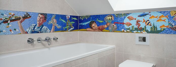 Blick in Badezimmer Richtung Badewanne und Toilette, dessen Wände mit einem Mosaikfries zum Thema "Wasser als Ressource" von Wolf v. Waldow gestaltet sind, Hergsteller: Firma Cosmomusivo Berlin.
