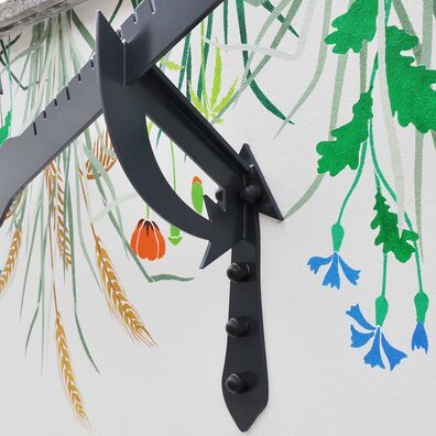 Silhouetten-Arbeit von Wolf v. Waldow: Stütze um Arbeit an Balkonbrüstung zu befestigen, Schablonenmalerei (Blumen) im Hintergund