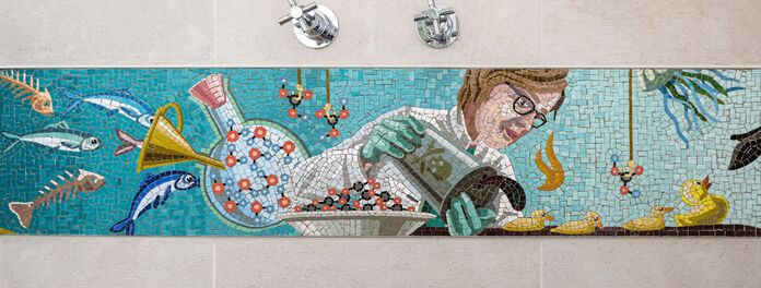 Ausschnitt Mosaikfries in Badezimmer zum Thema "Wasser als Ressource" von Wolf v. Waldow, Blick in Dusche mit Armatur; Motiv: Forscherin in weißem Kittel kippt Öl auf junge Entchen; Hergestellt durch die Firma Cosmomusivo Berlin
