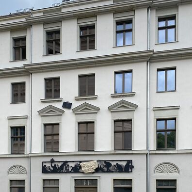Fassade Alter Markt 6, Potsdammit Kunst-Projekt "Wa(a)gnis" von Wolf v. Waldow: scherenschnittartiger, schwarzer Fries über Eingangstür mit weißem Reilieffragment; auf Attika Figurengruppe mit Frau, die Korb mit Waren ausschüttet, u. Mann davon abgewandt