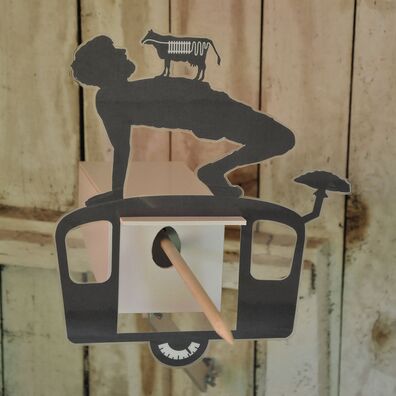 Projektraum "Hühnerhaus Volksdorf" mit Installation Neue Heimat von Wolf v. Waldow: Objekt in Form länglicher Überwachungs-Kamera, Front mit Motiv aus laminierten Papier das Junge, der gymnastische Übung auf Wohnwagen macht; auf seinem Bauch steht Kuh