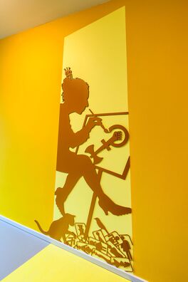 Lebensort Vielfalt Berlin, Projekt Storyboard – scherenschnittartige Figur aus Stahl auf Wand von Wolf v. Waldow, Motiv: Frau malt an einem feministischen Zeichen, auf dem Boden WC-Zeichen für Frauen.