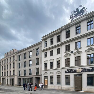 Blick Häuserzeile Alter Markt 6, Potsdam bis Landtag Brandenburg, No 6  mit Kunst-Projekt "Wa(a)gnis" von Wolf v. Waldow an Fassade: scherenschnittartiger, schwarzer Fries über Eingangstür mit Relieffragment; auf Attika Figurengruppe mit Frau und Mann